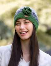 A woman wearing a purple and grey crochet knitted cap with a flower corsage on the side.